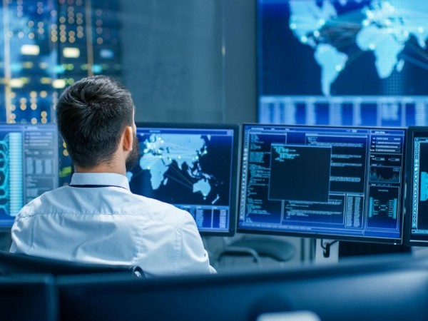 Homme face à plusieurs écrans (illustration cybersécurité)